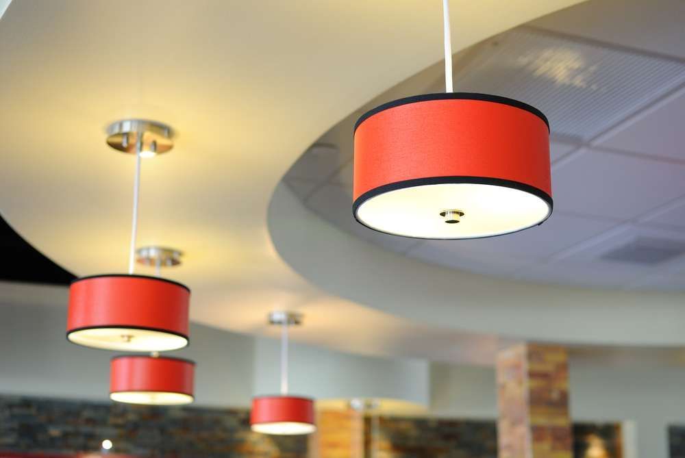 Red cylindrical pendant lights hanging from a curved white ceiling.
