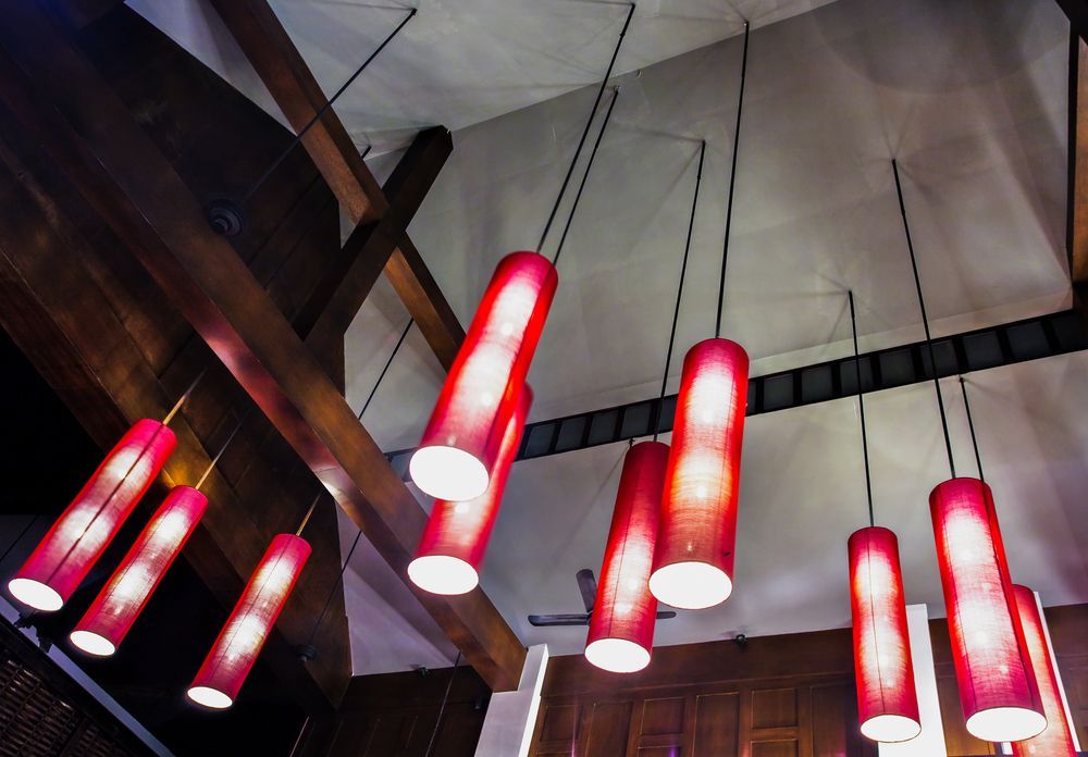 Red cylindrical pendant lights hanging from a wooden beam ceiling.