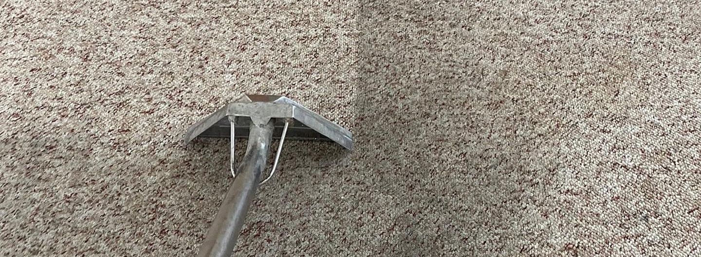 A tool with tines resting on a textured, neutral-toned surface.