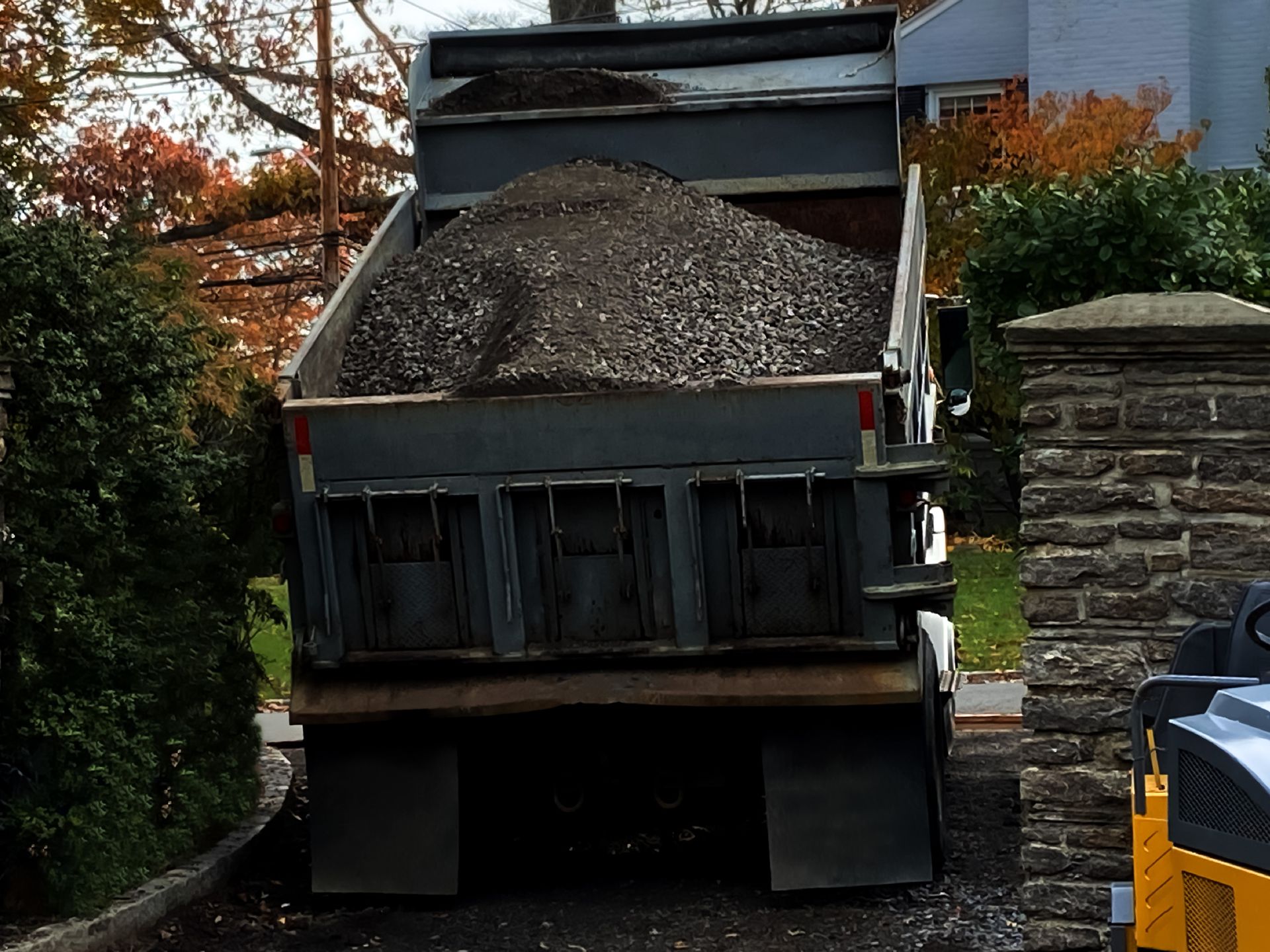 A Dump Truck Filled with Gravel Is Parked in Front of A Stone Wall — Paving Contractors In Butler, PA