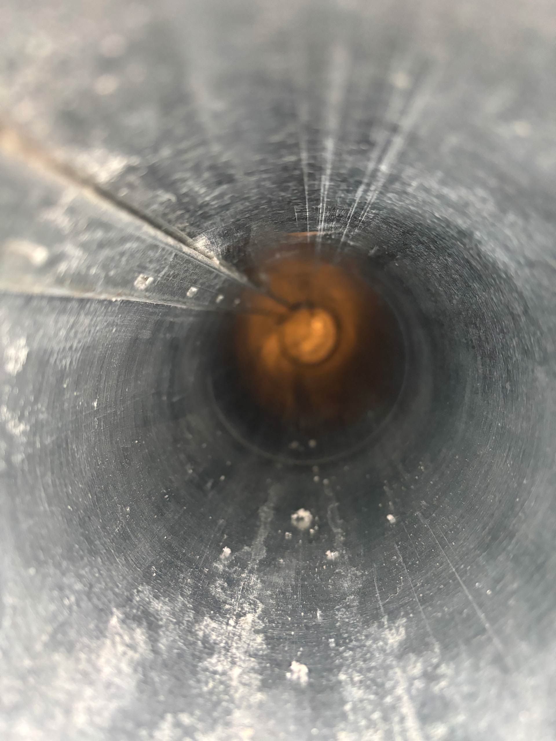 A close up of the inside of a metal pipe with a hole in the middle.