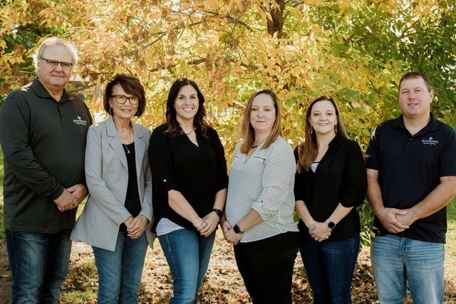 A group of people standing next to each other in front of a tree.