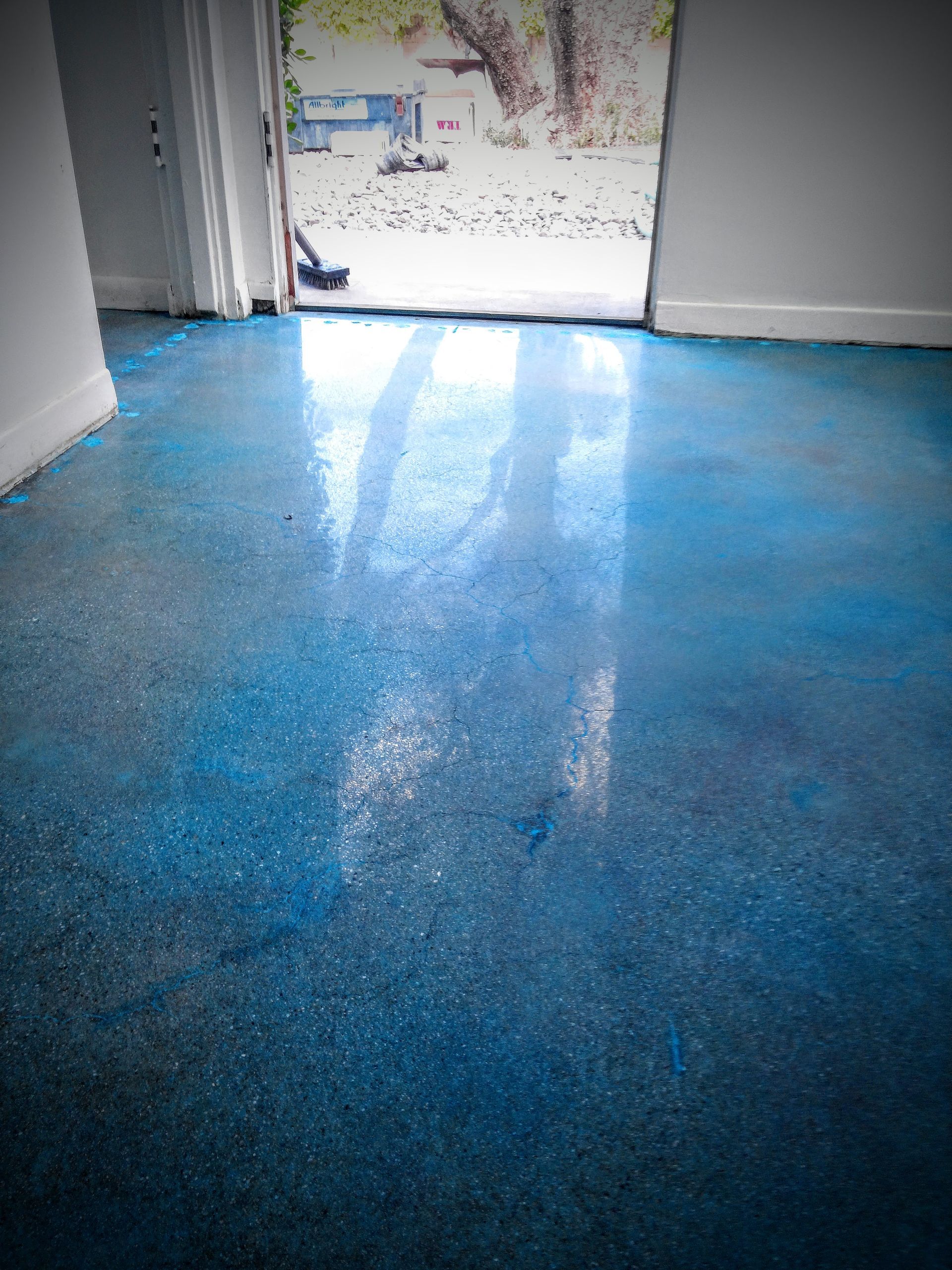 A blue floor in a room with a sliding glass door.