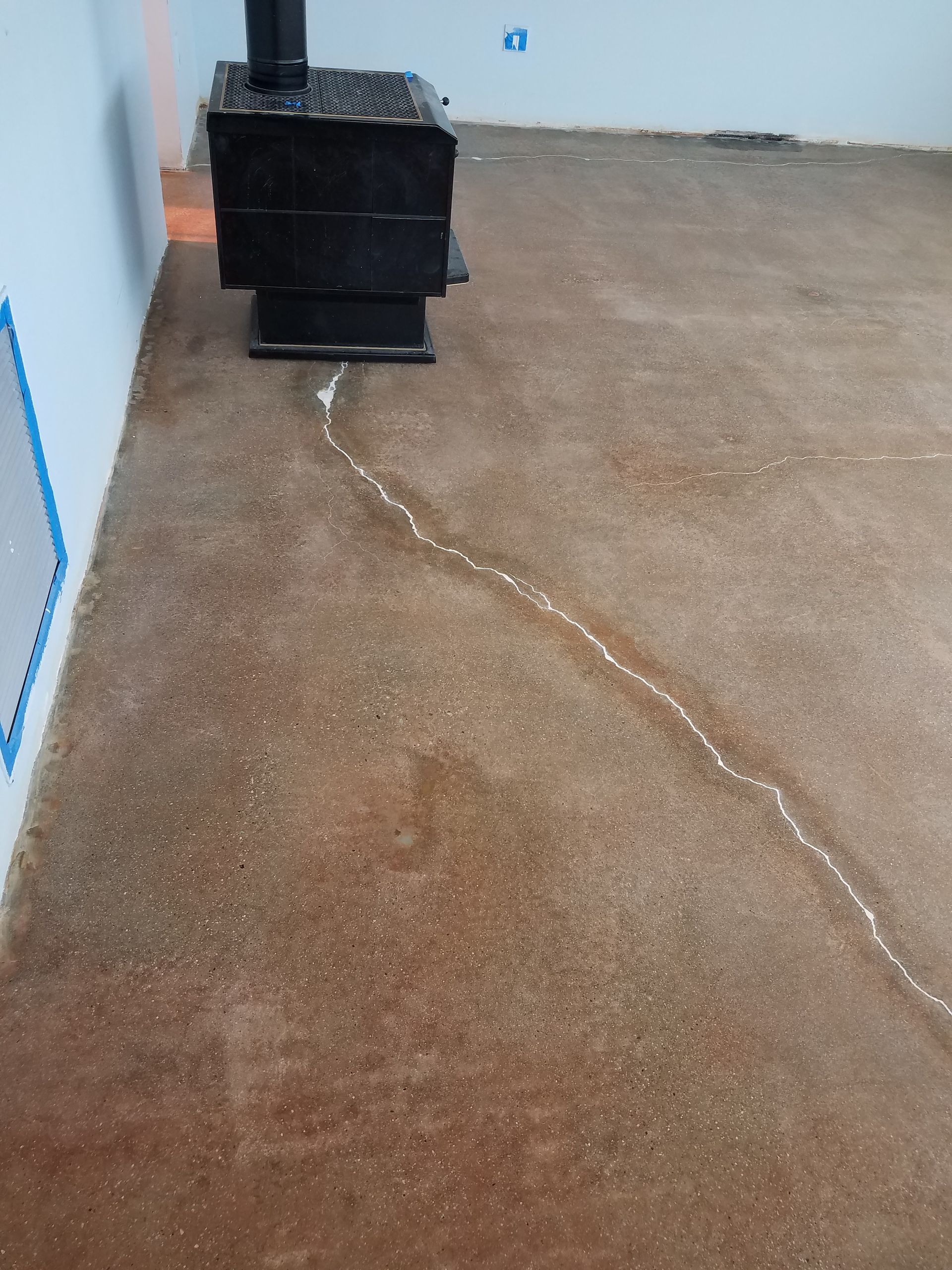 A wood stove is sitting on a concrete floor in a room.