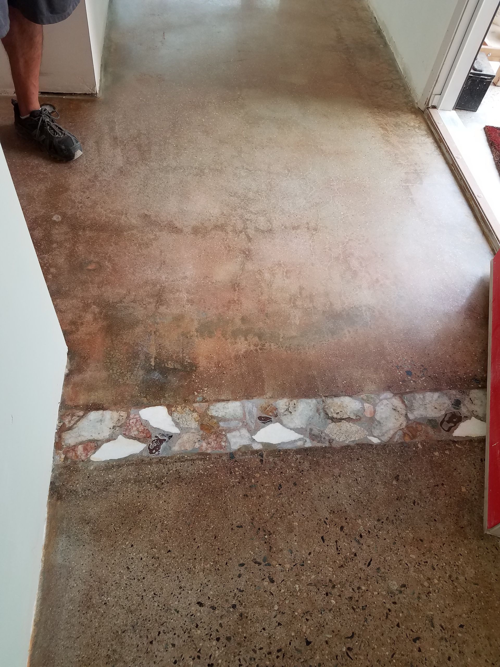 A person is standing on a tiled floor in a hallway.