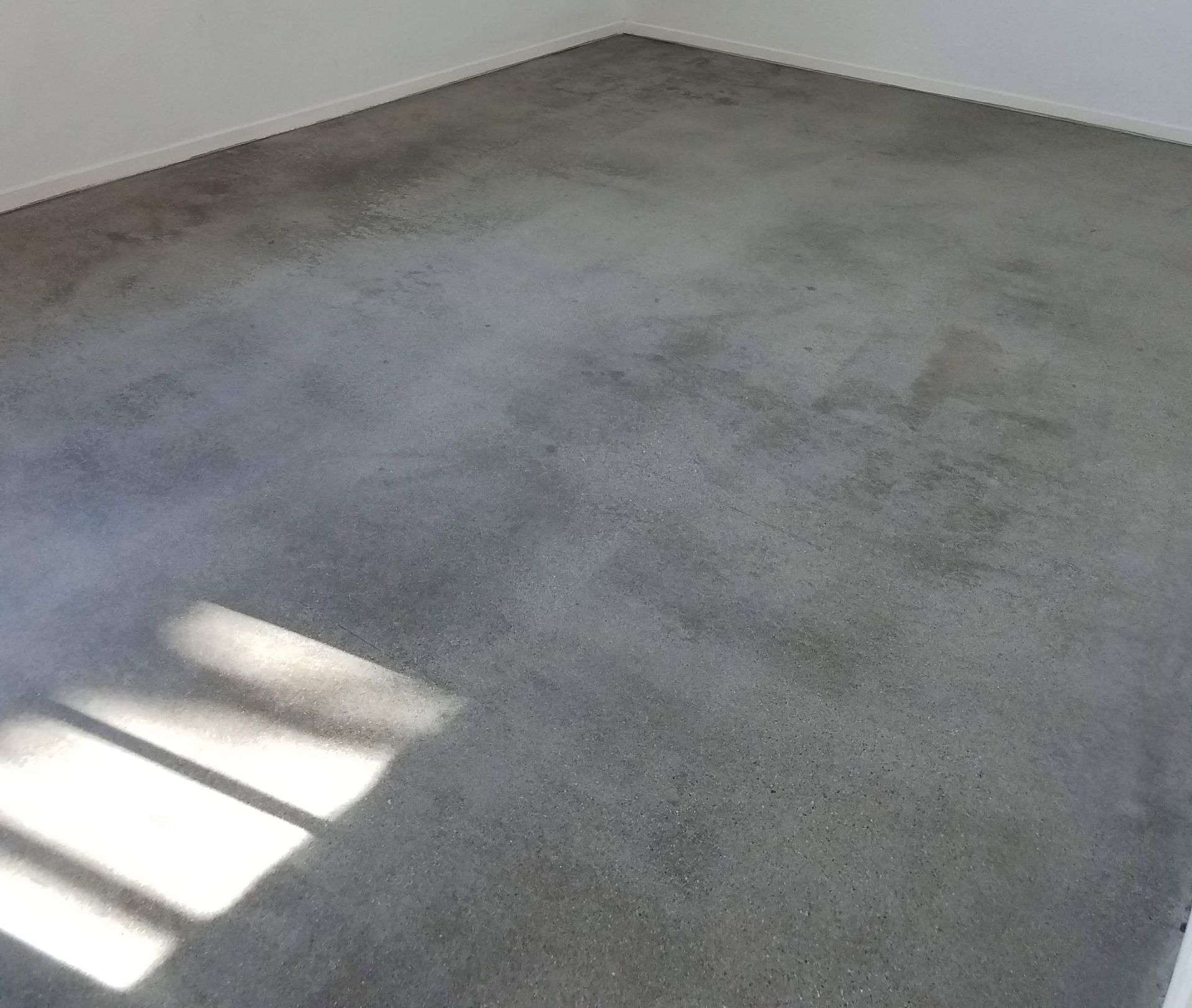 A room with a gray concrete floor and white walls.