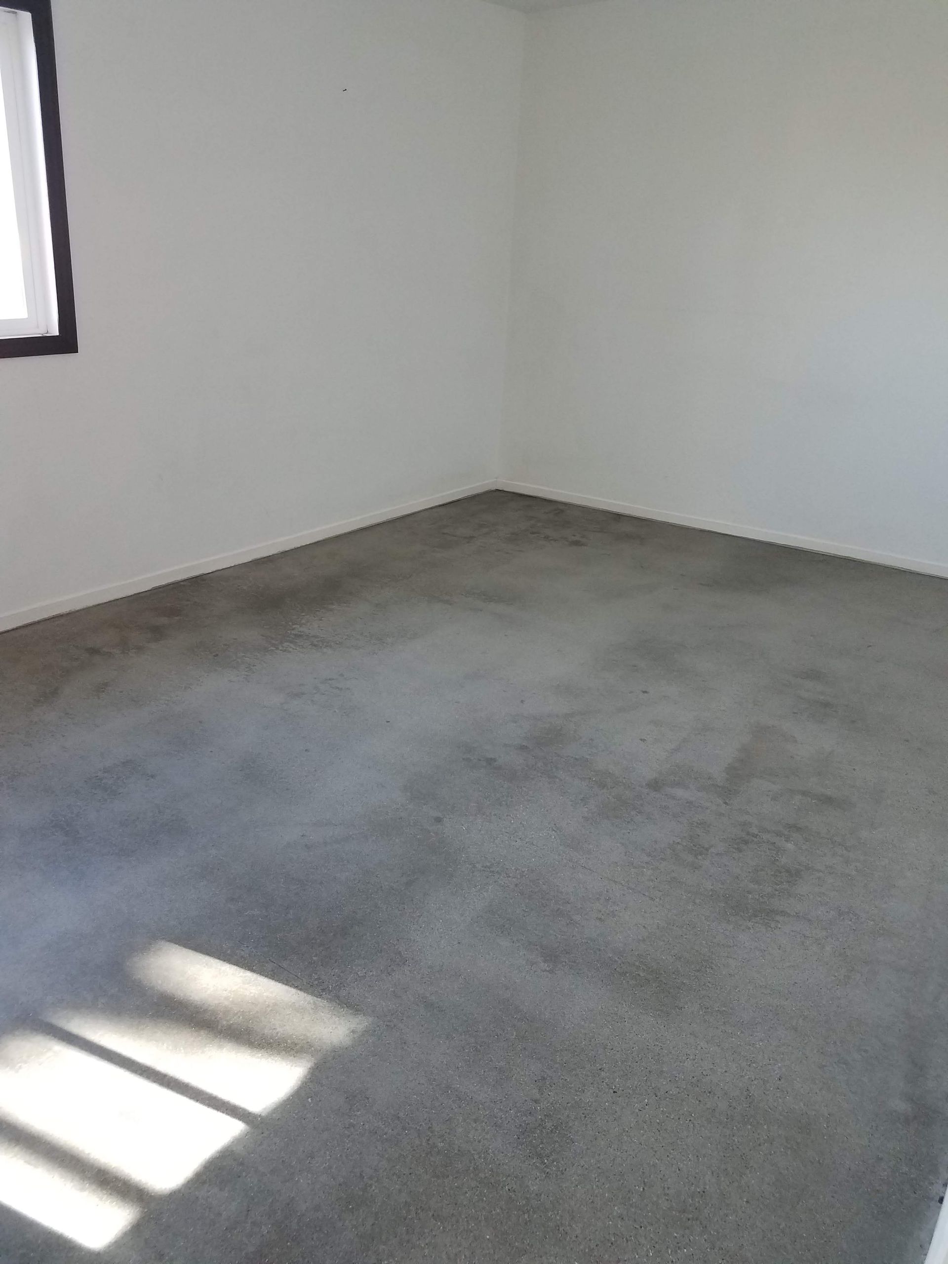 An empty room with a large carpeted floor and a window.