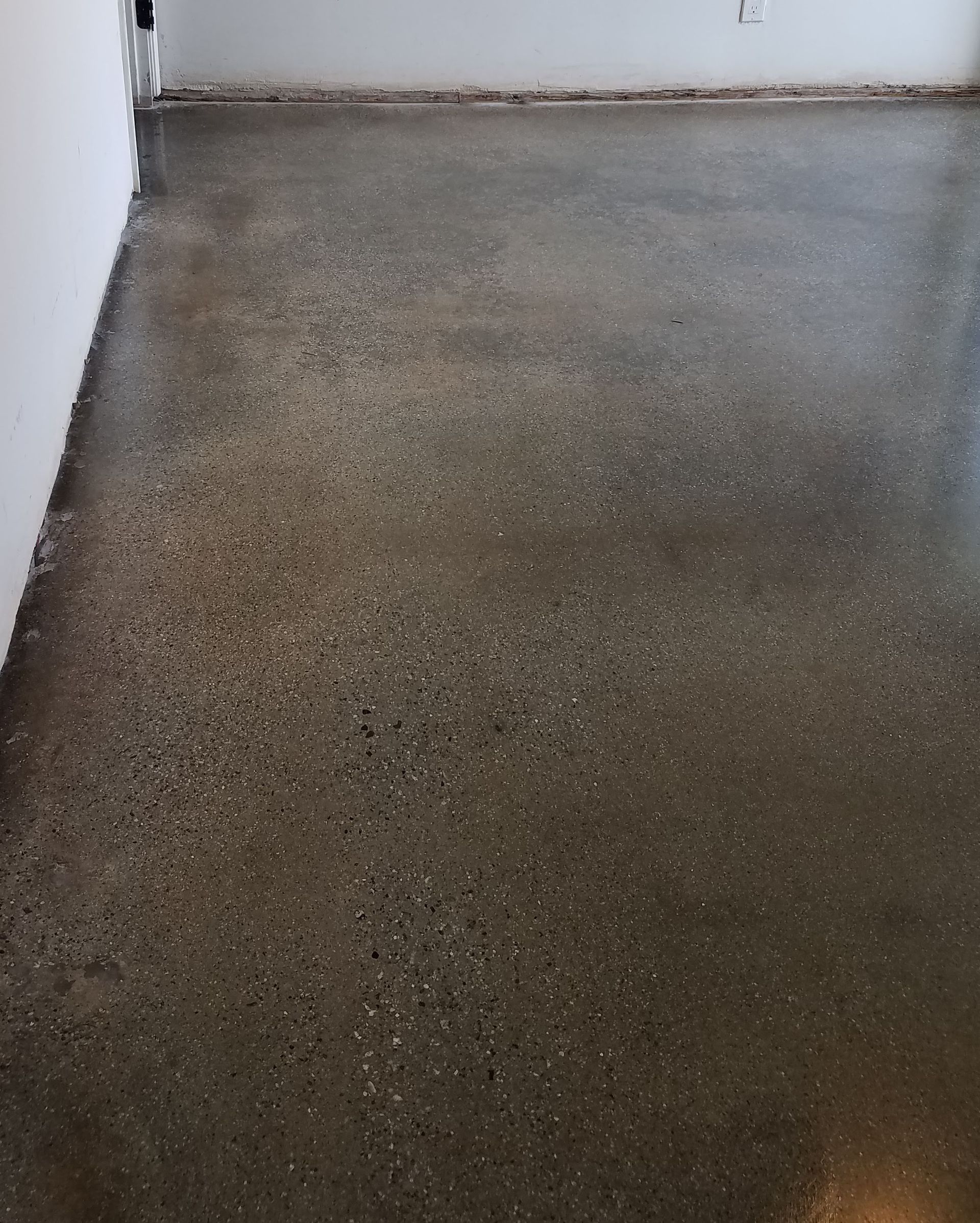 A concrete floor in a room with a white wall.