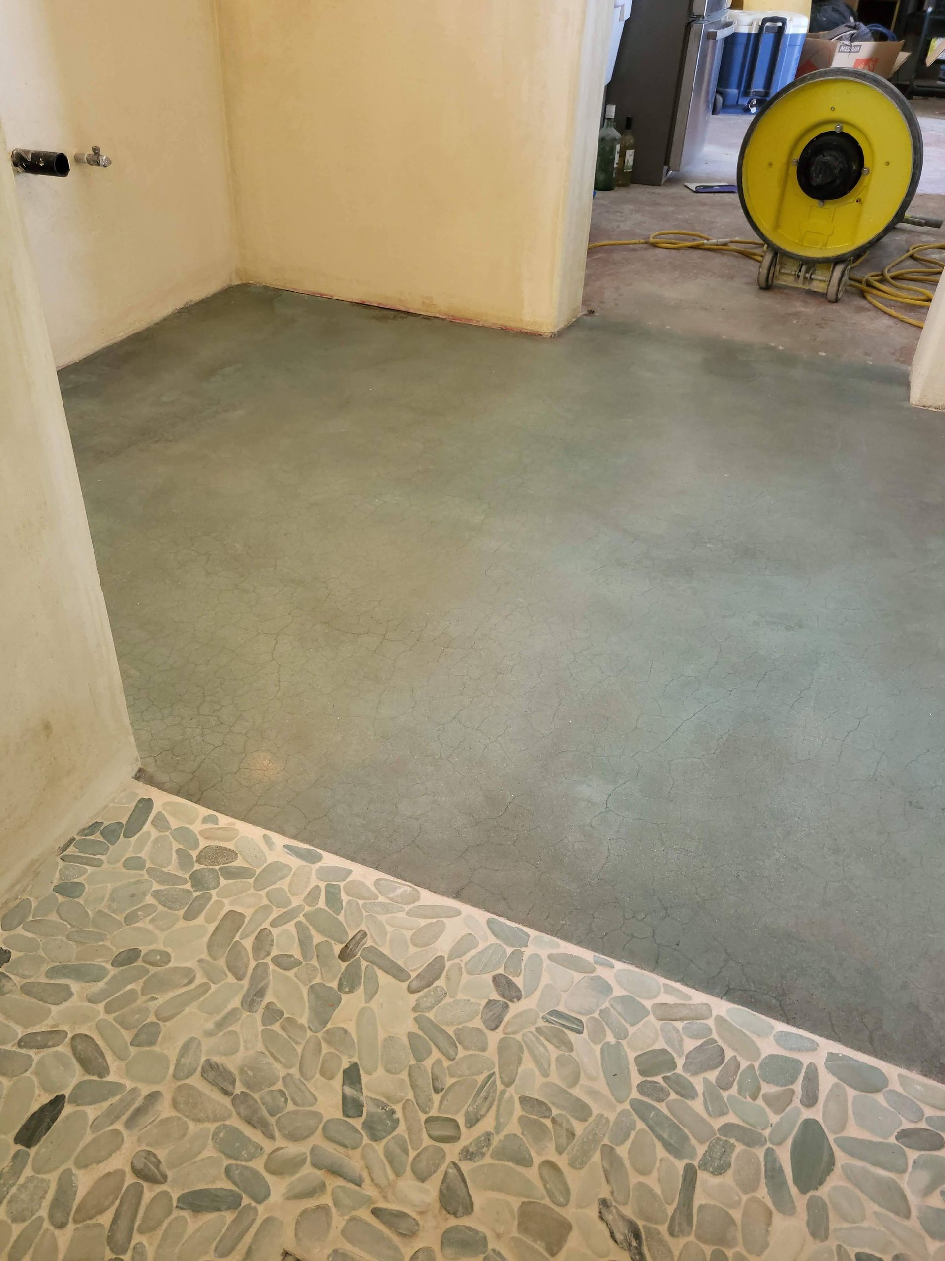 A room with a tiled floor and a fan on the floor.