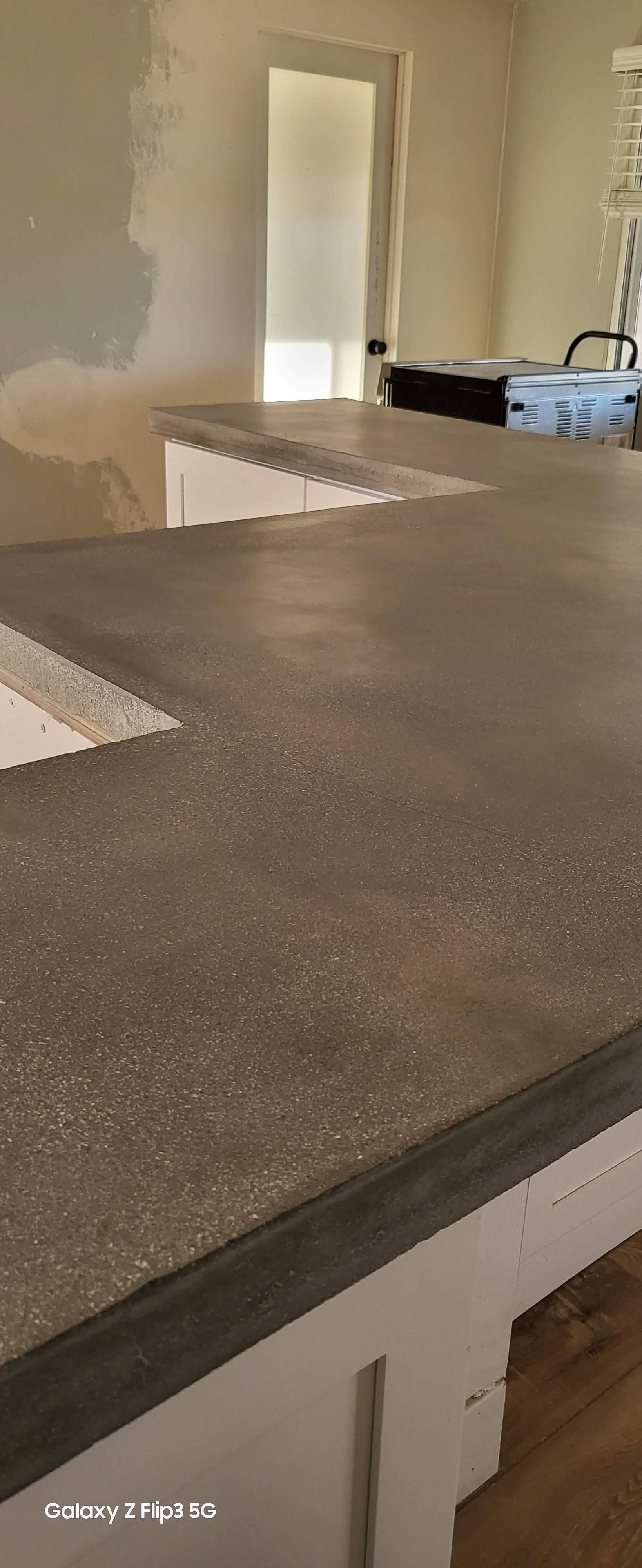 A kitchen counter with a gray counter top and white cabinets.
