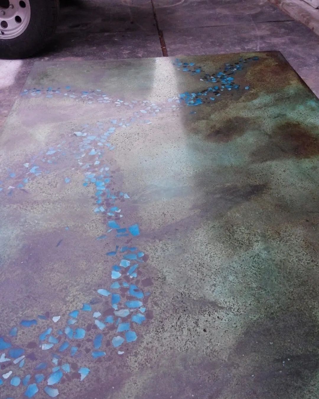 A concrete floor with a painting on it and a tire in the background.