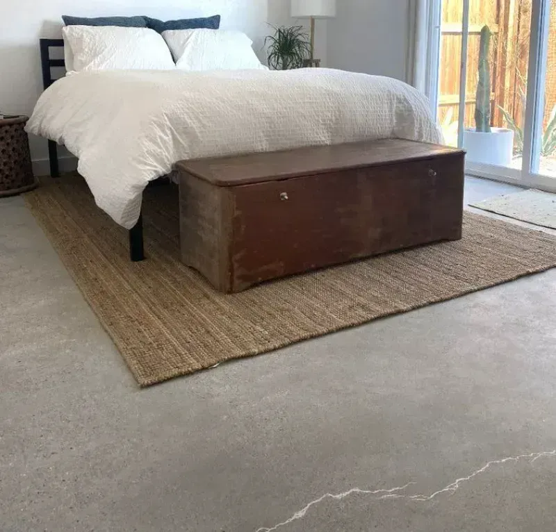 a bedroom with a bed and a trunk on the polished concrete floor in La Quinta CA.