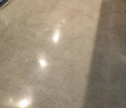 A close up of a shiny concrete floor with a shadow on it.