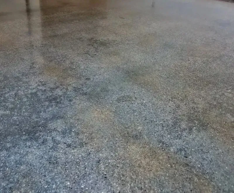 A close up of a concrete floor with a lot of small stones on it.