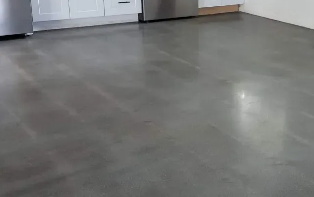 Polished concrete floor in a kitchen, reflecting light; grey surface.