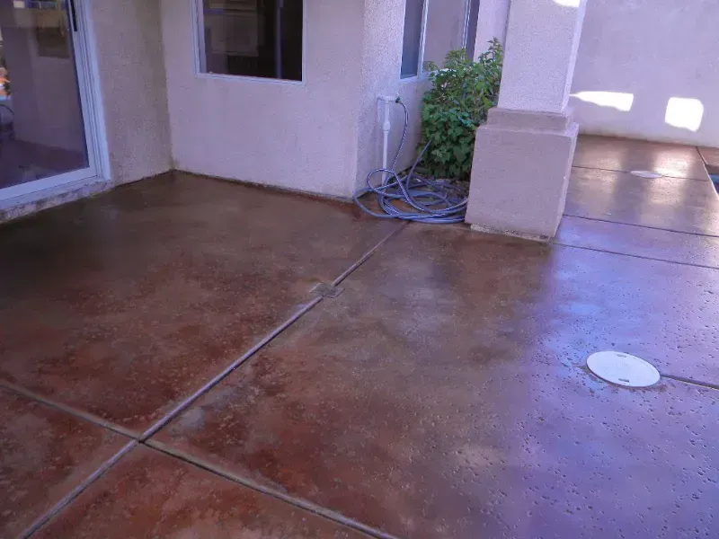 A concrete patio with a hose connected to it and a window.