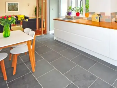 a kitchen with a table and chairs, a cleaned grout and black tile floor in Palm Springs California