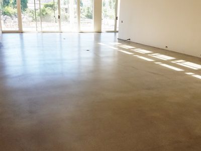 A large empty room with a concrete polished floor and sliding glass doors.