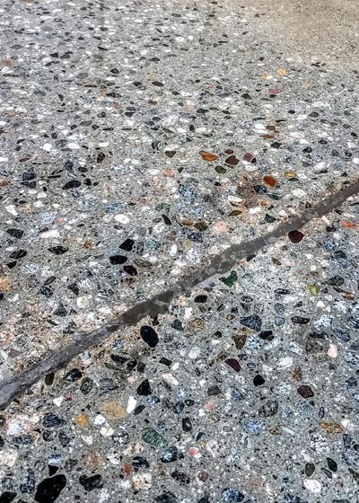 A paint roller applies a wet, gray coating to a concrete floor.