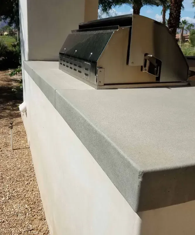 a grill is sitting on top of a white concrete countertop in Yucca Valley, South California.