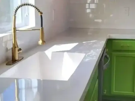 a kitchen sink on a concrete countertop with a gold faucet and green cabinets in Yucca Valley, South California.