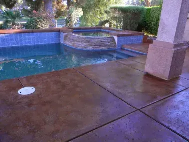 Poolside patio with a brown stained concrete surface, pool, and spa.