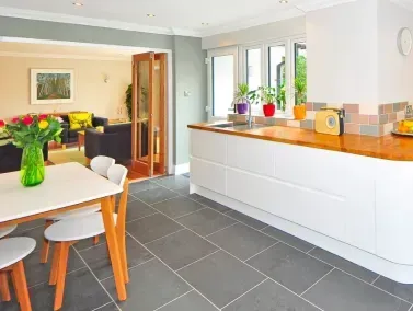 a kitchen with a table and chairs, a cleaned grout and black tile floor in Palm Springs California