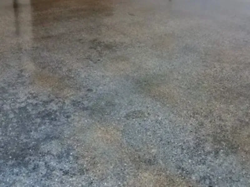 A close up of a concrete floor with a lot of small stones on it.