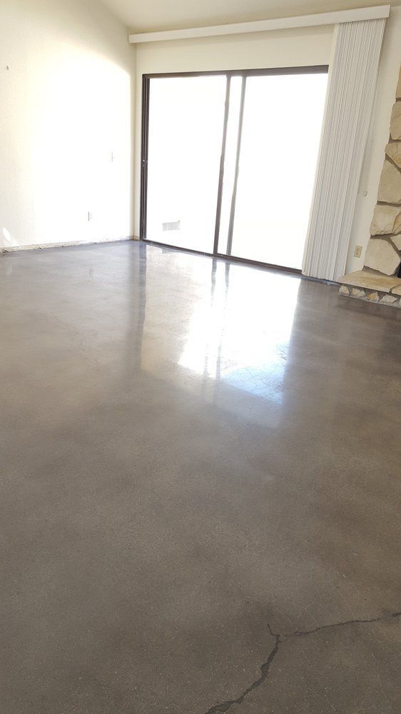 An empty living room with sliding glass doors and a polished concrete floor.