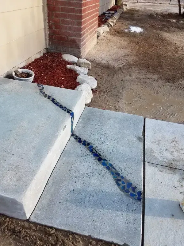 A concrete sidewalk with a brick wall in the background