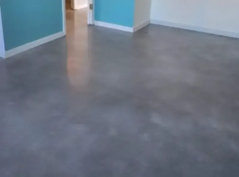 A polished concrete floor in a room with white walls and bright turquoise accent walls.