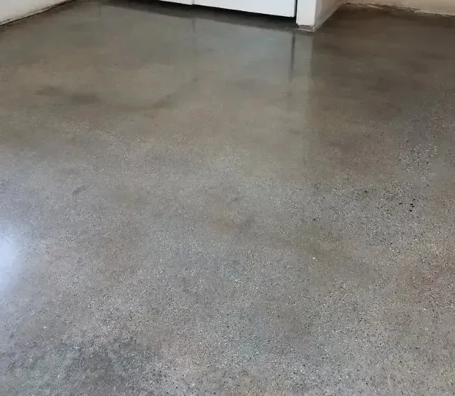 Polished, gray concrete floor with subtle variations in tone, reflecting light.