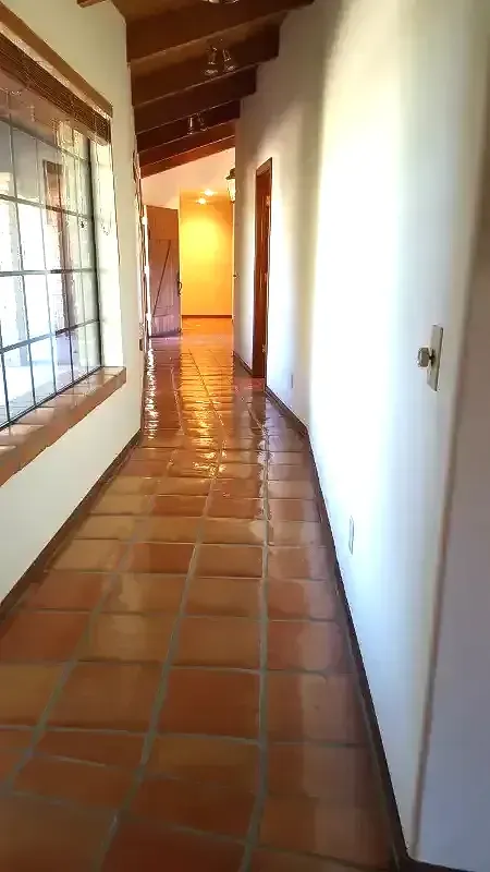 A long hallway with tile floors and white walls in a house.