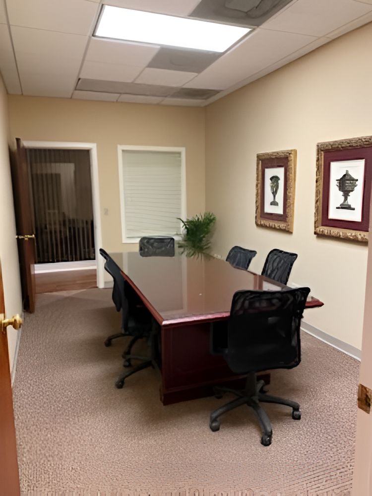 A conference room with a wooden table and chairs and a whiteboard on the wall.