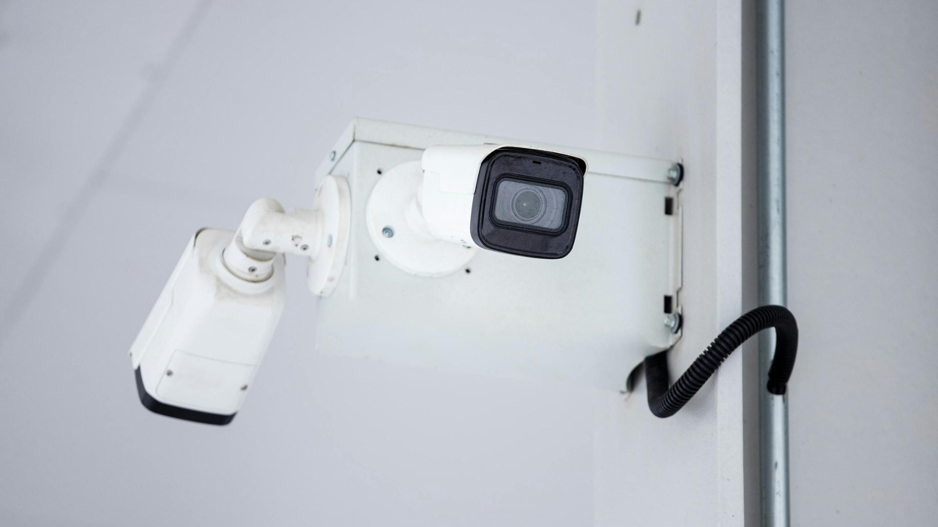 A security camera is mounted on a white wall.