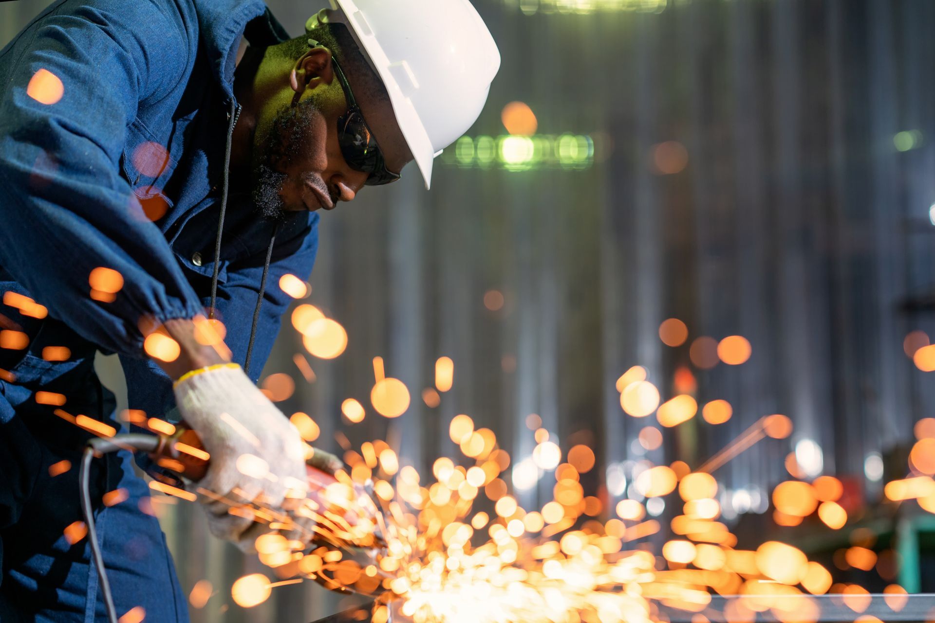 Industrial worker with electric grinder tools grinding the surface of a metal workpiece