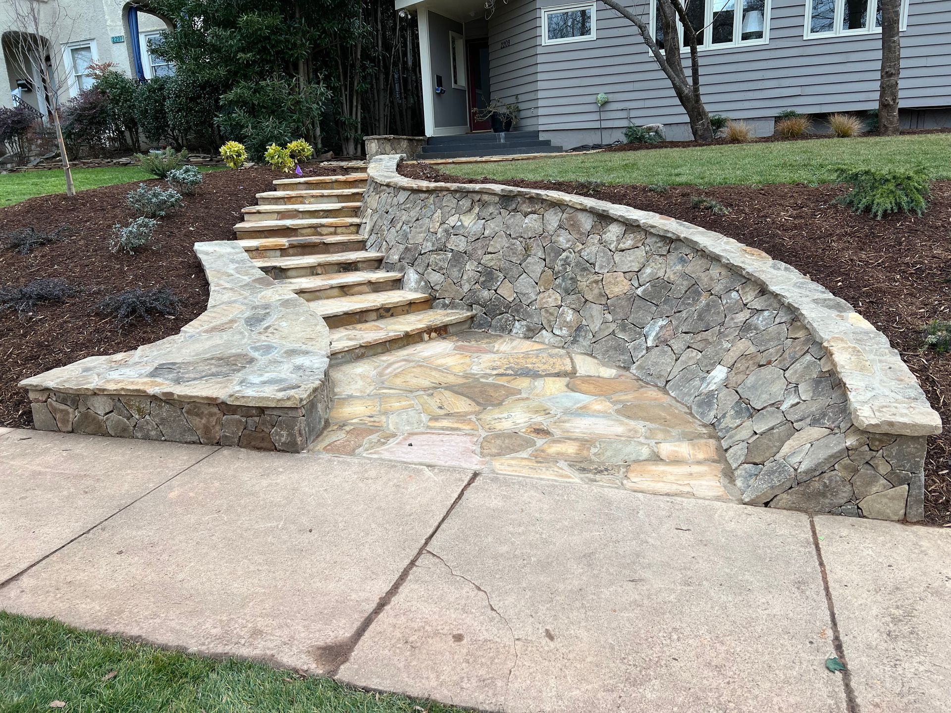 A stone wall with stairs leading up to a house.
