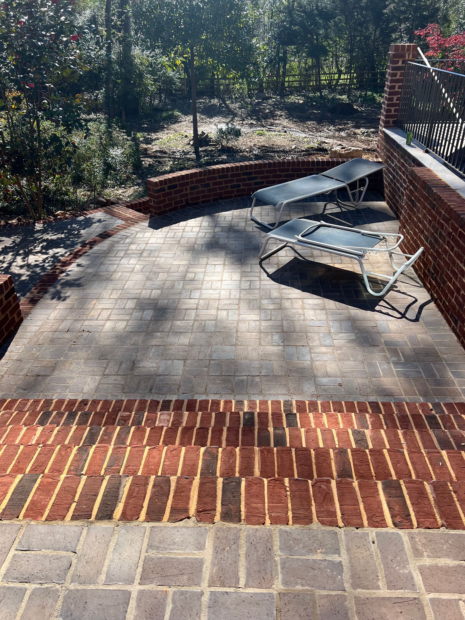 A brick patio with chairs and trees in the background