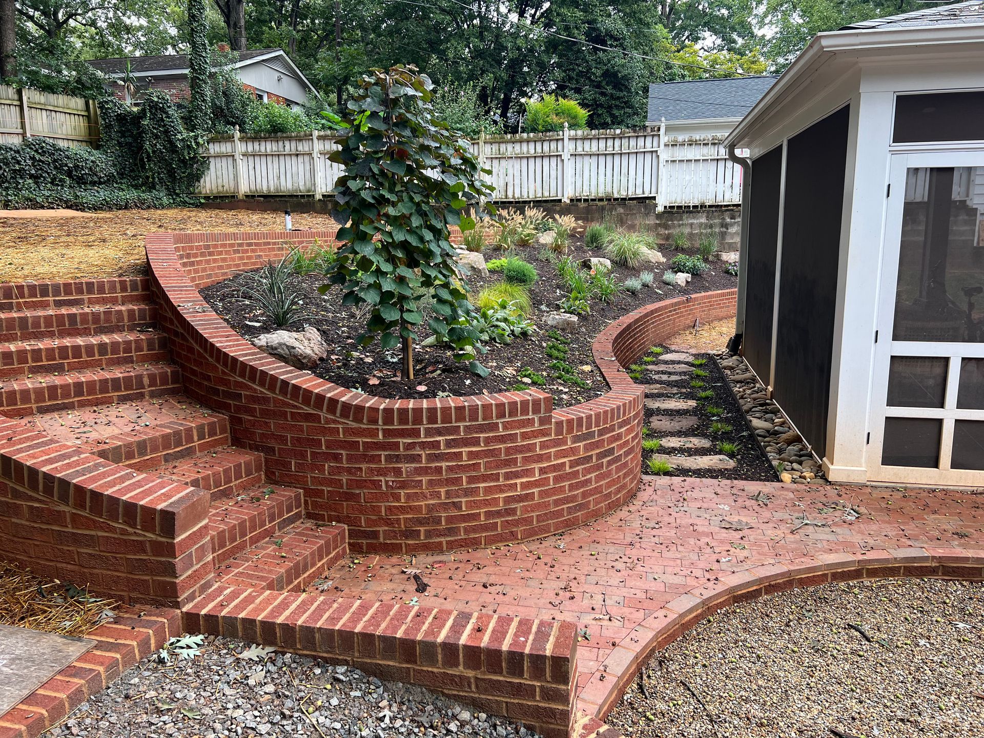 A brick walkway with stairs leading up to a screened in porch.