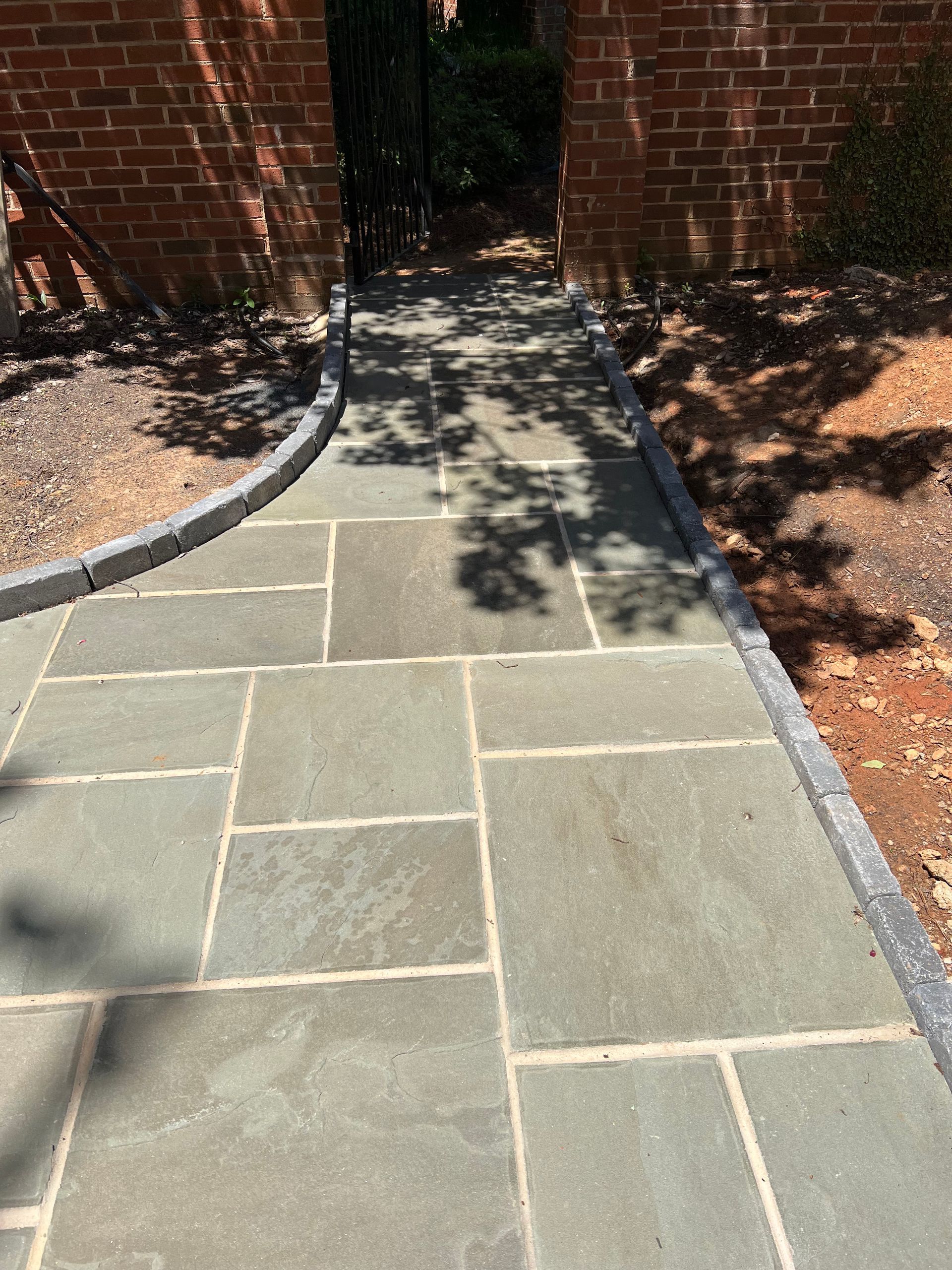 A stone walkway with a brick wall in the background.