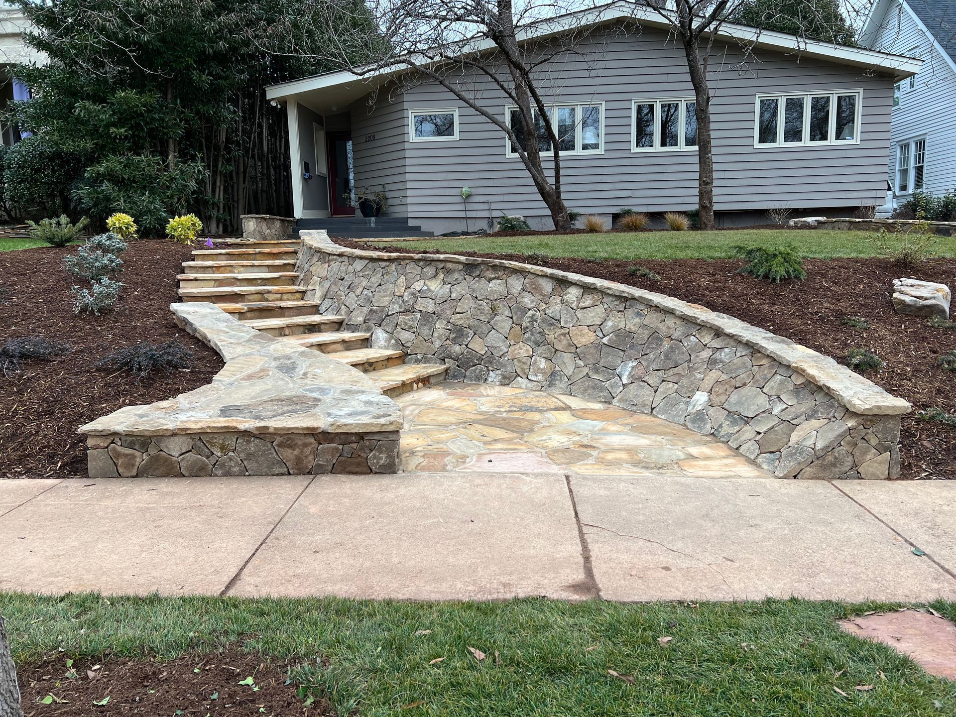 A stone wall with stairs leading up to a house.