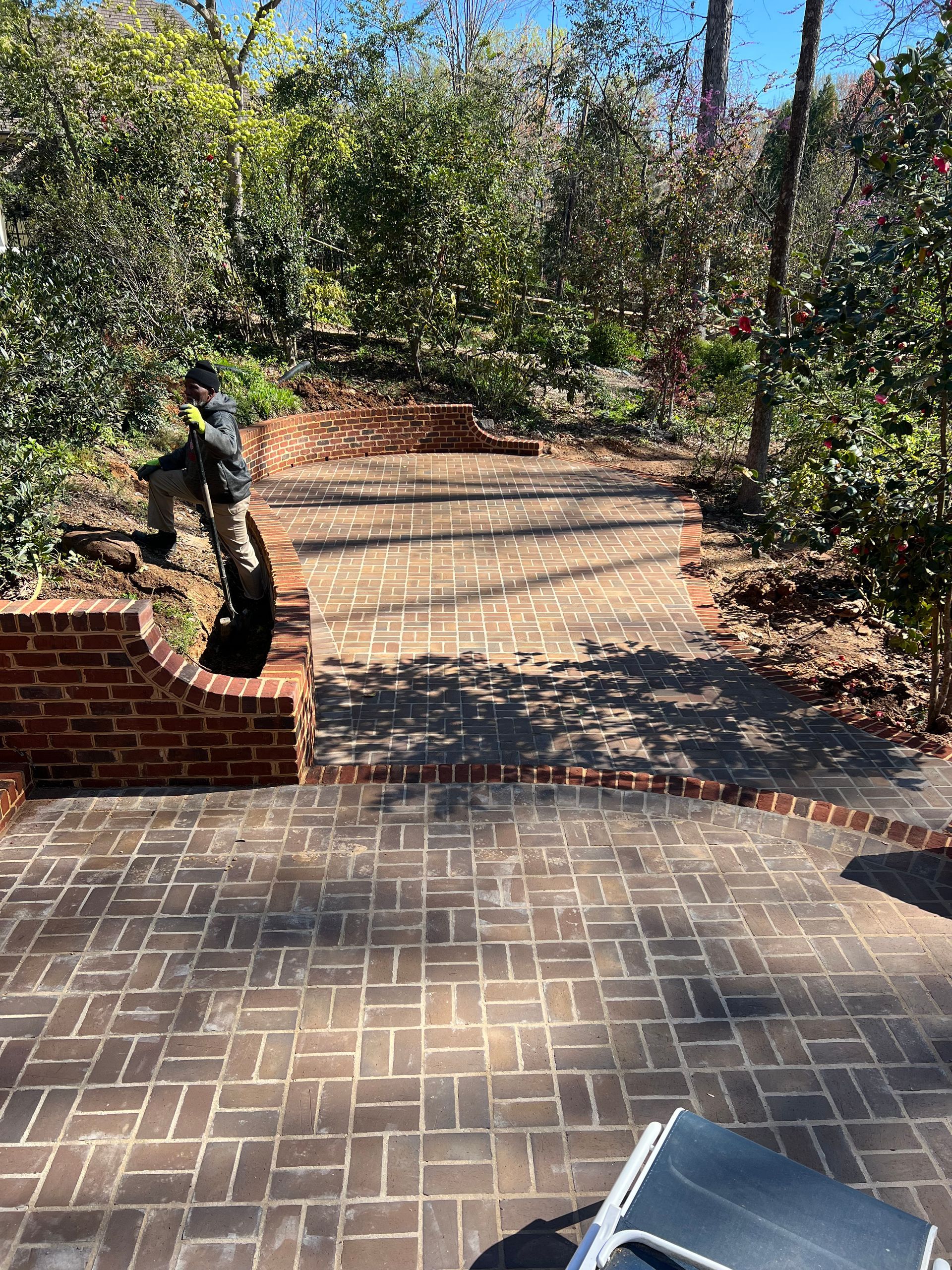 A man is standing on a brick walkway in a park.