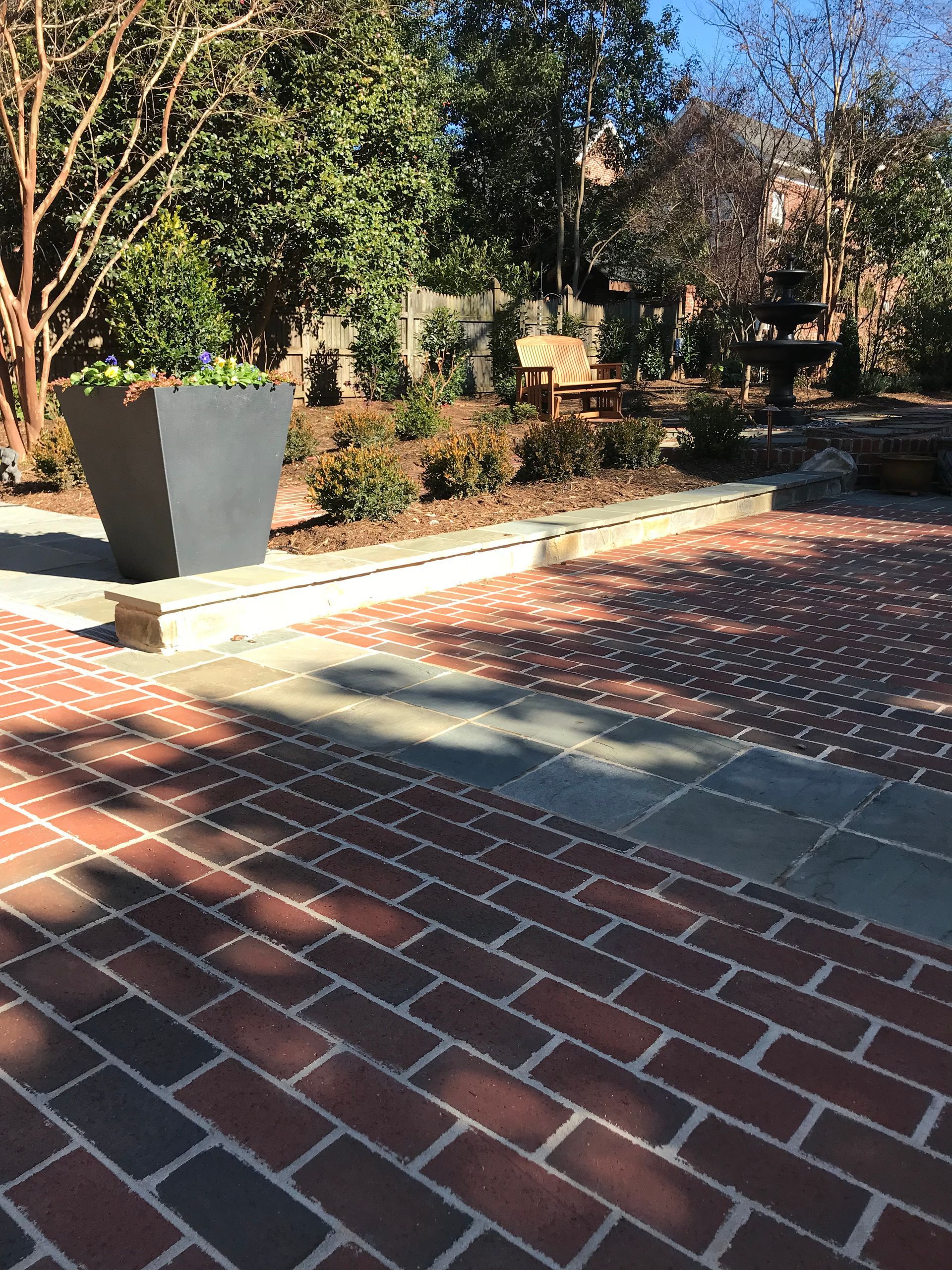 A brick walkway with a planter in the middle of it