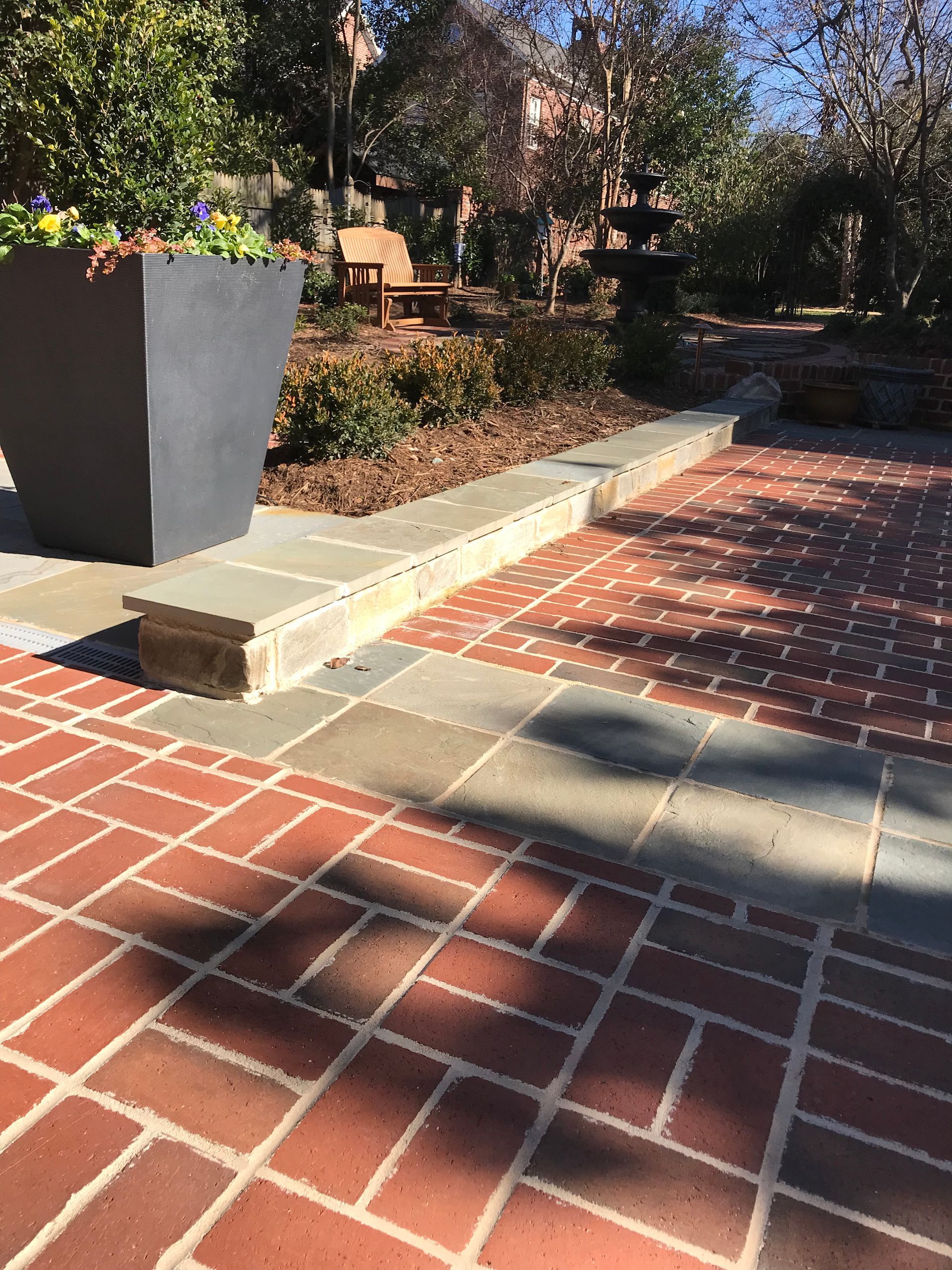 A brick walkway with a planter in the background
