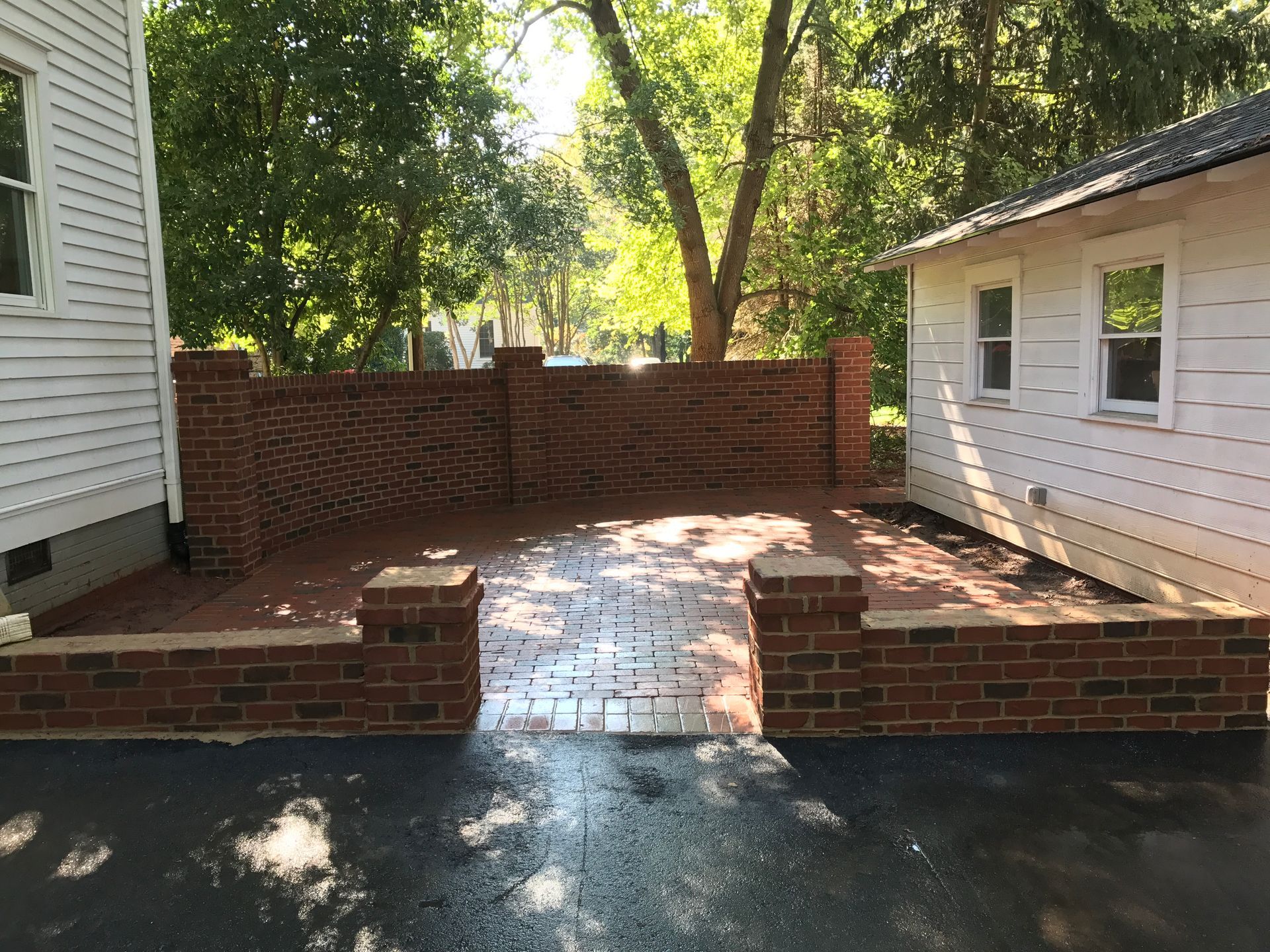 There is a brick wall between the house and the driveway.