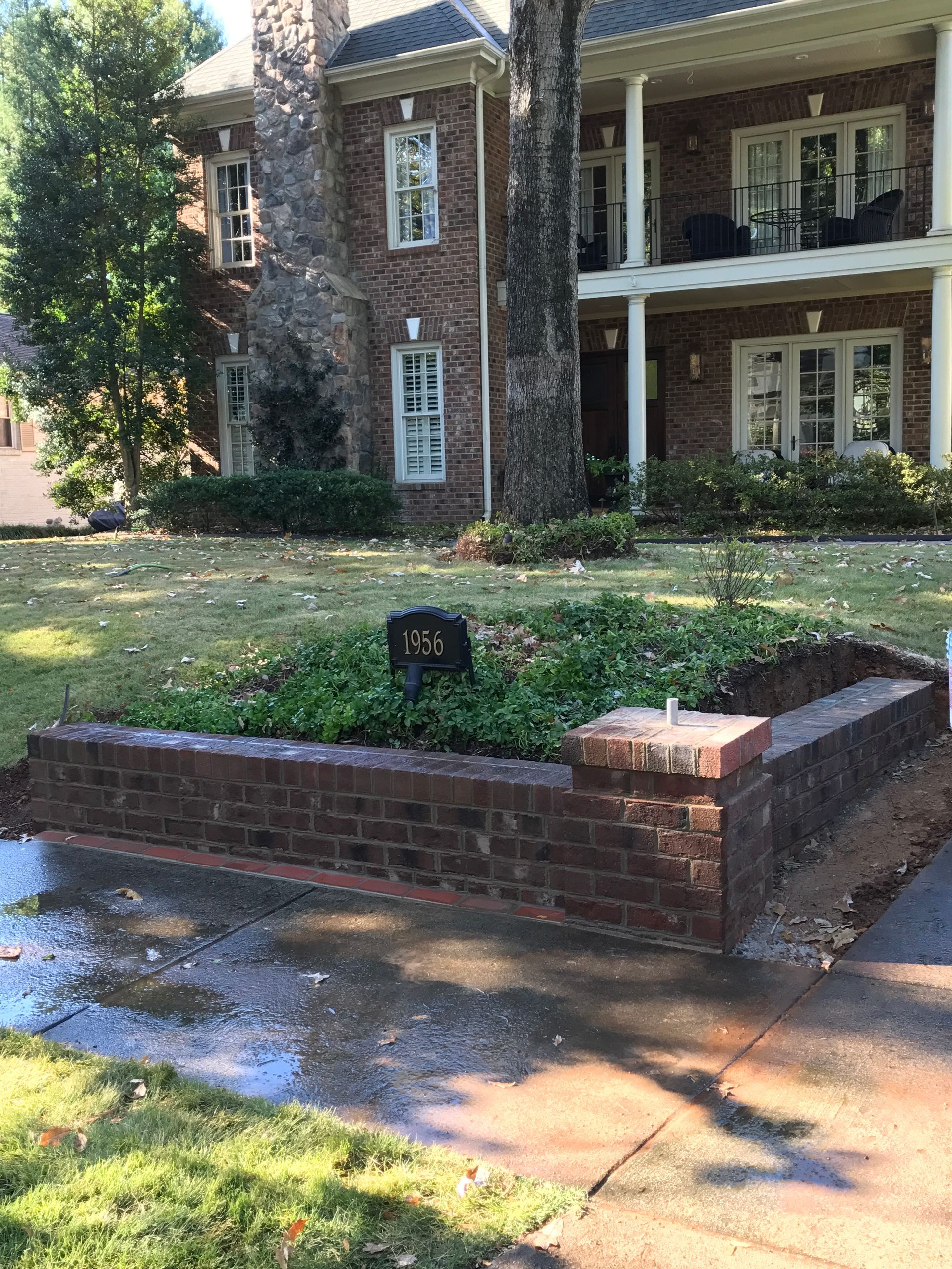A large brick house with a brick planter in front of it.