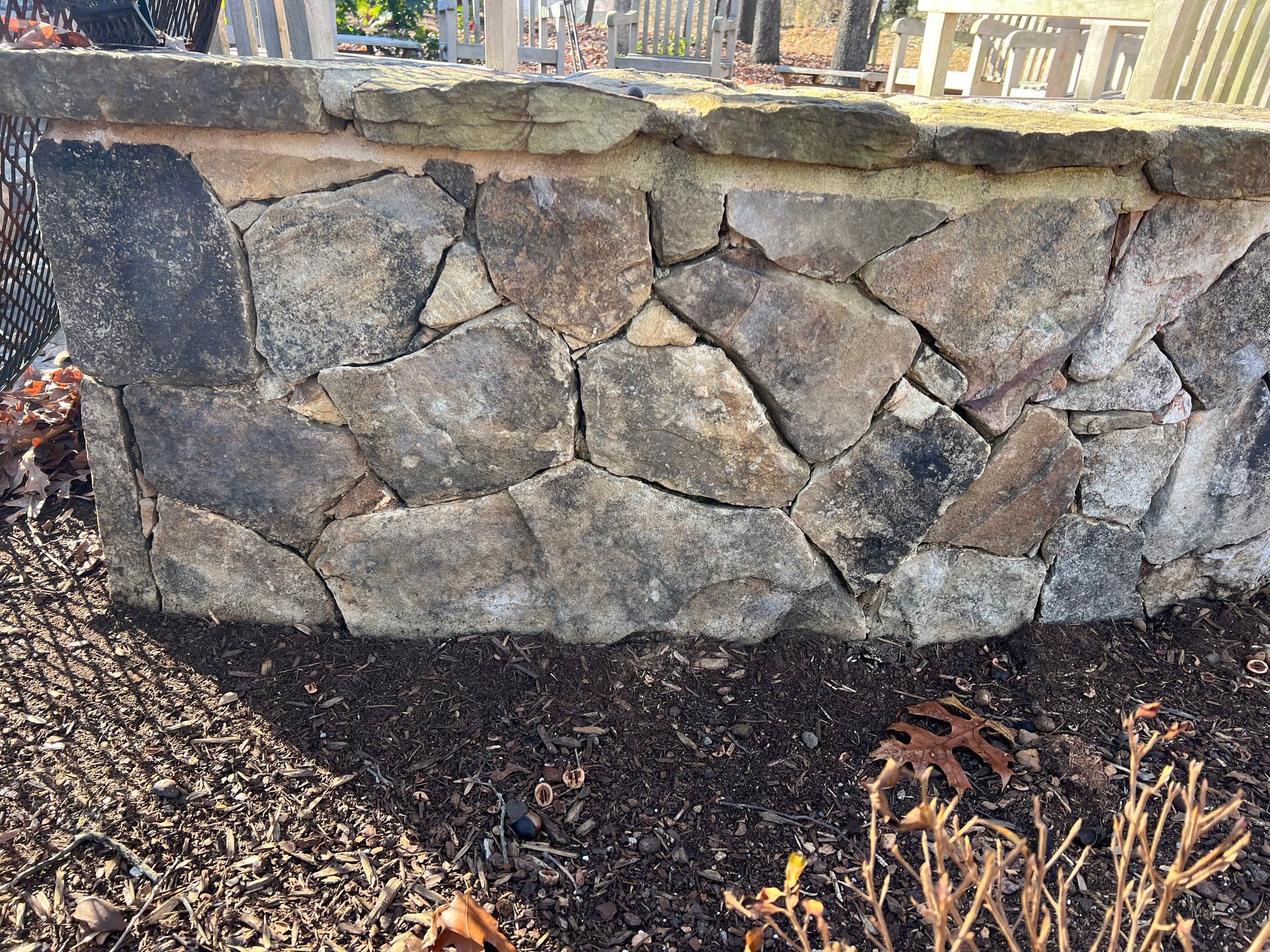 A stone wall is sitting in the middle of a pile of mulch.