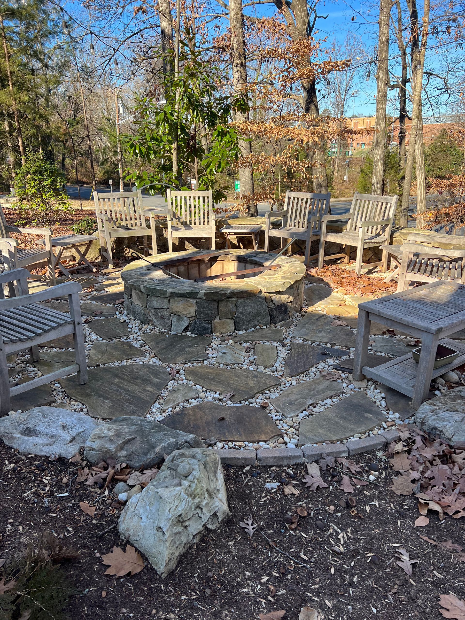 A fire pit surrounded by rocks and chairs in the middle of a forest.
