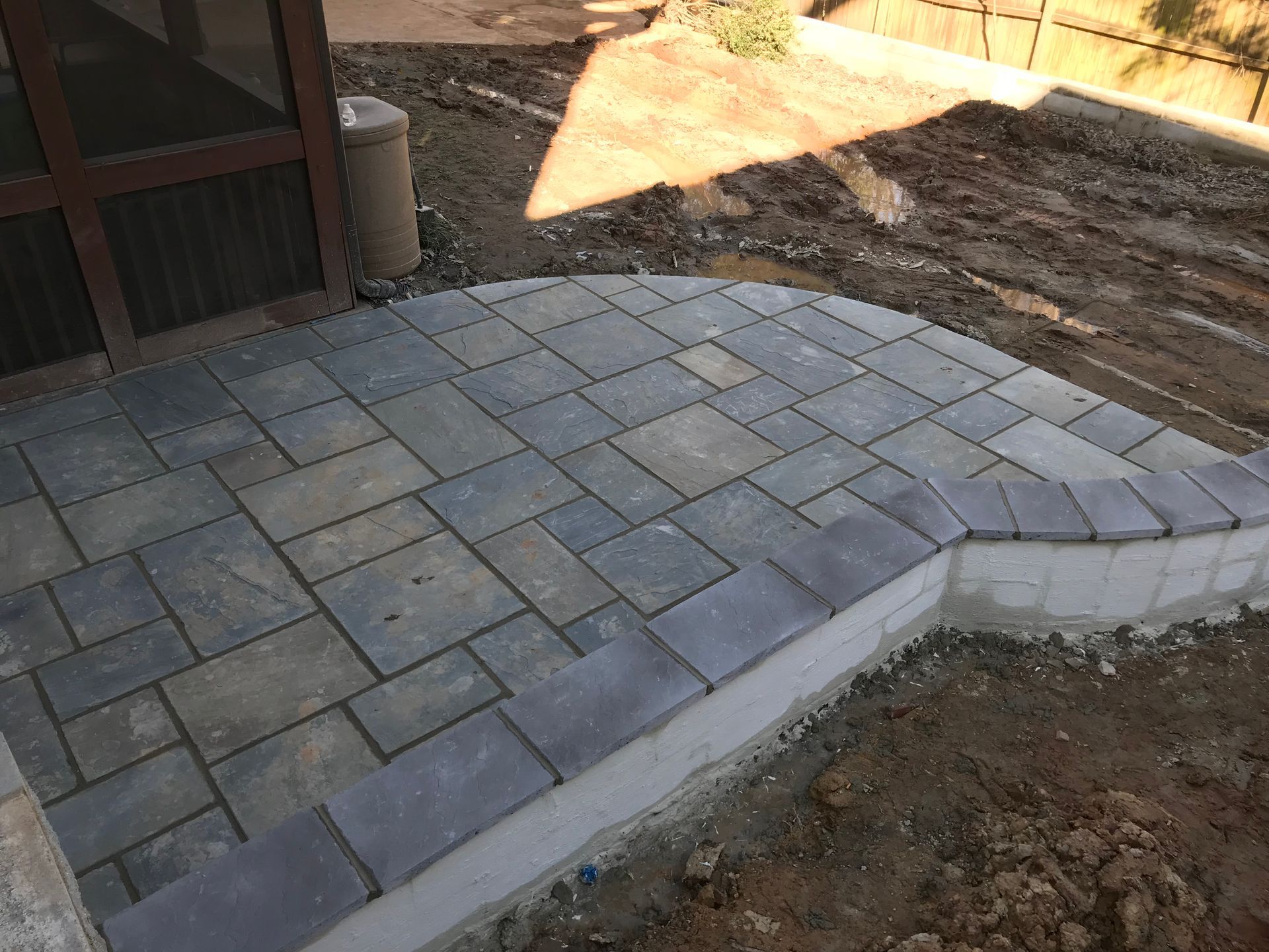 A patio is being built in a backyard with a screened in porch.