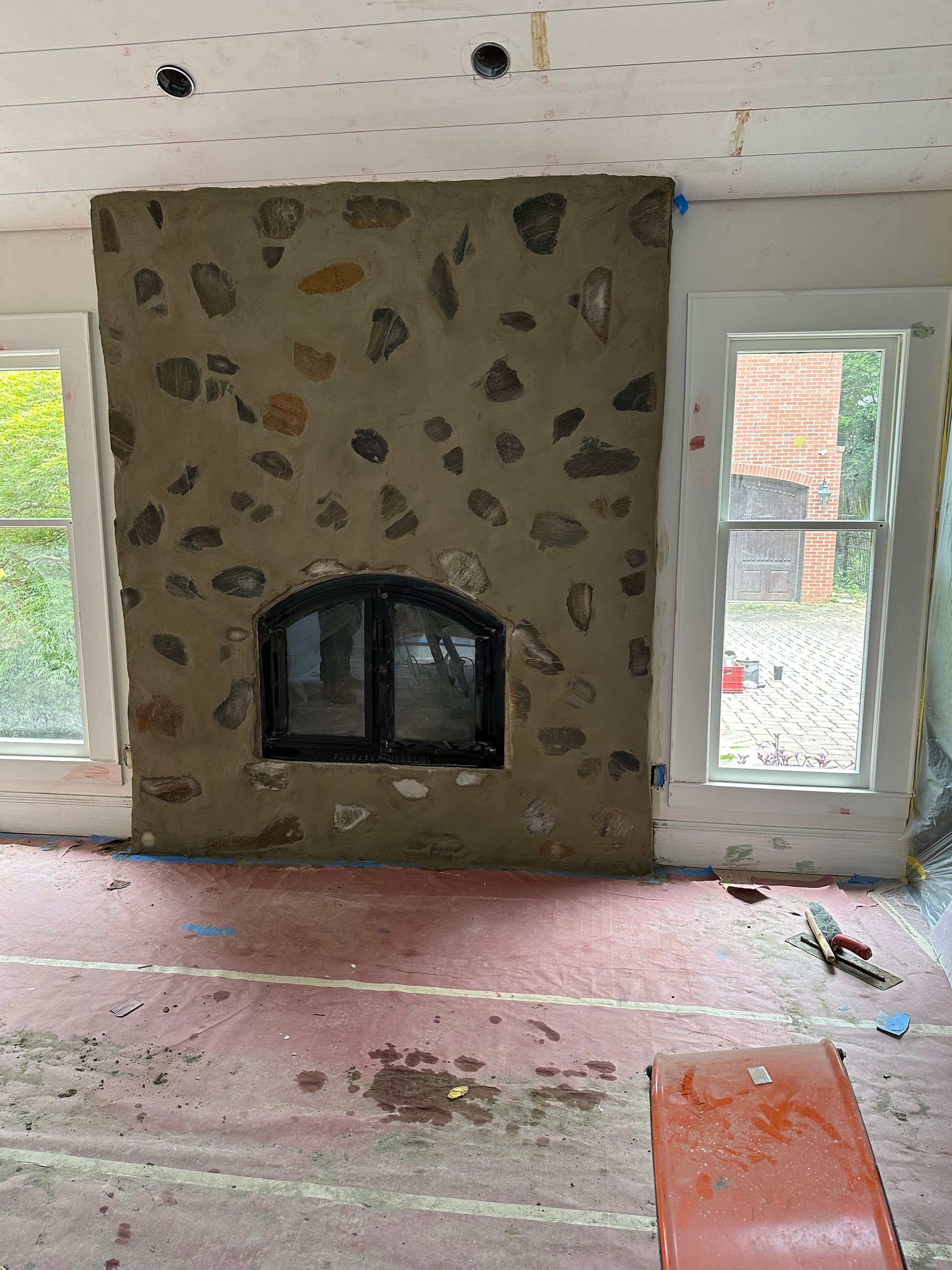 A stone fireplace is being built in a living room.